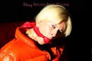 Pia tied and gagged on a chair wearing a shiny orange down jacket and a shiny blue rain pants (Pics)