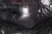 Lucy wearing a supersexy black rain catsuit posing and lolling on a sofa (Pics)