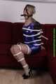 Sophie bound with Leatherbelts and Harnessgagged wearing a shiny purple Dress