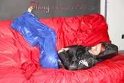 Sonja wearing a blue shiny nylon raver pants and a black down jacket posing and lollingn on the sofa (Pics)