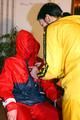 Jill tied by her friend in shiny yellow and red rainsuits