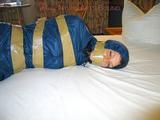 One of our archive girls bound and gagged in a blue shiny rainsuit 