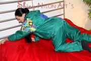 Lucy putting on linen on bed wearing supersexy green shiny nylon rainwear (Pics)