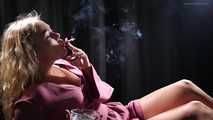 Blonde girl is smoking a cigarette is the dark room