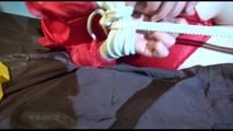 Lucy tied and gagged on bed wearing a red/yellow shiny nylon shorts and a red rain jacket (Video)