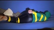 Mara tied, gagged and hooded with tape on a blue sofa wearing an blue/green rain combination (Video)