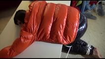 Mara tied and gagged on a table wearing a sexy black down pants and an orange down jacket (Video)