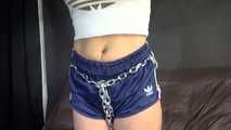 Watching sexy Sandra wearing an darkblue shiny nylon shorts and a white adidas top being tied and gagged overhead with ropes, chaines and a ballgag (Video)