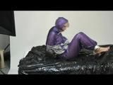 Pia bound and gagged on bed in a shiny purple/silver PVC sauna suit (Video)