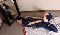 Emily in violet short-sleeve and jeans, hog-cuffed with steel cuffs, wiggles on the floor