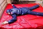 Pia hooded, tied and gagged on bed in a dark blue old school down ski suit