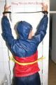 Stella tied, gagged and hooded on an radiator wearing a shiny red/blue rain combination (Pics)