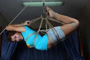 Barefoot Roxana, suspended with ropes, is tickled and teased by a camera man