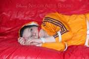 Lucy tied and gagged on a sofa wearing an orange shiny nylon rain jacket and a blue rain pants (Pics)