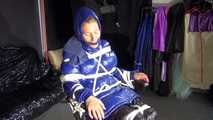Watching sexy Sandra wearing a sexy blue shiny nylon rainpants and a blue down jacket being tied and gagged and hooded with ropes on a hairdressers chair covered with a rain cape (Video)