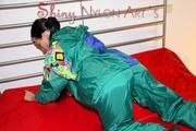 Lucy putting on linen on bed wearing supersexy green shiny nylon rainwear (Pics)