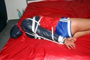 Alina bound in blue shorts and a shiny jacket