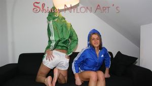 Katharina and Sabrina lolling on a sofa both wearing shiny nylon shorts and rain jackets (Pics)