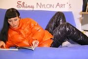 Mara wearing a sexy black down pants and an orange down jacket while lolling and reading on the sofa (Pics)
