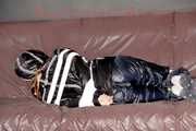 Mara wearing a sexy shiny black rian pants and a sexy shiny black rain jacket tied and gagged with tape and cloth gag on a sofa (Pics)
