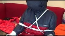 Jill tied, gagged and double hooded on a chair wearing shiny nylon shorts and two shiny nylon rain jackets (Video)