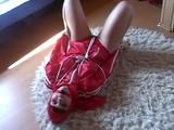 Black haired archive girl tied, gagged and hooded on the floor wearing a shiny red nylon shorts and a shiny red rain jacket (Video)