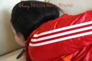 Jill tied and gagged lying on a sofa wearing a sexy shiny red adidas shorts and a red rain jacket (Pics)