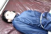 Jill tied, gagged and hooded in bed wearing a sexy green shiny nylon shorts and a shiny rain jacket (Video)