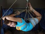 Barefoot Roxana, suspended with ropes, is tickled and teased by a camera man