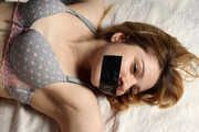 Barefoot tapegagged Grace in grey lace polka dot bra and panties, tied on the bed with her hands and legs wide-spread, wiggles helplessly