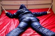 Pia hooded, tied and gagged on bed in a dark blue old school down ski suit