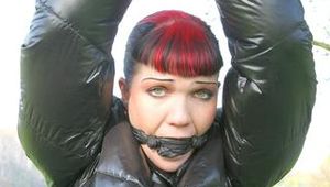 Jill tied and gagged outdoor on a tree wearing a sexy black downjacket and a black rain pants (Pics)