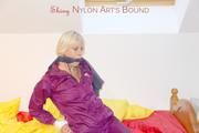 Pia in a shiny purple rainsuit tied and gagged in bed (Pics)