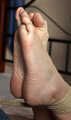 Ballgagged barefoot Carolyn, hogtied with hemp rope, wiggles on the bed