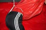 Sonja wearing a black rain pants and a red shiny nylon rain jacket tied and gagged with ropes overhead (Pics)