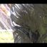 Mara wearing sexy black shiny rainwear while playing with the water of the sprinkler (Video)