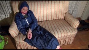Mara tied, gagged and hooded on an old sofa wearing a cool blue rain skirt and a jacket as well as rubber boots (Video)