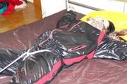Lucy tied and gagged in a bed wearing a black shiny nylon downwear combination (Pics)