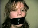 HEATHER IS F0RCED TO TAPE UP HER LEGS AND BARE FEET & IS THEN PANTY STUFFED AND WRAP GAGGED THEN HOG-TIED WITH TAPE ON THE BED (D52-14)