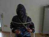 An archive girl tied, gagged and hooded two times on a sofa and chair wearing a shiny blue rainwear (Video)