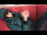 Alina wearing a sexy shiny crazy sensation skibib in blue and a green special down jacket reading on a sofa and playing with cuffs (Video)