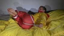 Watching Sandra  wearing an orange shiny nylon rain pants and a yellow shiny nylon rain jacket being tied and gagged on a bed with ropes and a clothgag (Video)