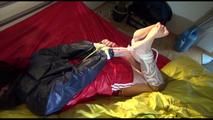 Jill tied and gagged on a bed wearing an sexy shiny nylon shorts and an oldschool rain jacket (Video)