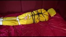 Lucy tied, gagged and hooded on a sofa with dark ropes wearing a sexy yellow rainwear combination (Video)