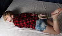 Ballgagged barefoot Carolyn, hogtied with hemp rope, wiggles on the bed