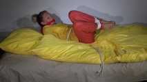 Watching Sandra  wearing an orange shiny nylon rain pants and a yellow shiny nylon rain jacket being tied and gagged on a bed with ropes and a clothgag (Video)