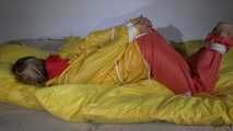 Watching Sandra  wearing an orange shiny nylon rain pants and a yellow shiny nylon rain jacket being tied and gagged on a bed with ropes and a clothgag (Video)