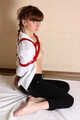 Topless barefoot Polina in unbuttoned white shirt and black jeans, bound with red ropes, poses on the floor