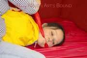***LUCIE*** wearing red/yellow shiny nylon shorts and a yellow shiny nylon rain jacket being bound on a sofa with ropes and a ball gag (Pics)