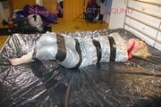Pia tied and gagged with tape on a bed wearing a sexy silver rainwear combination (Pics) 